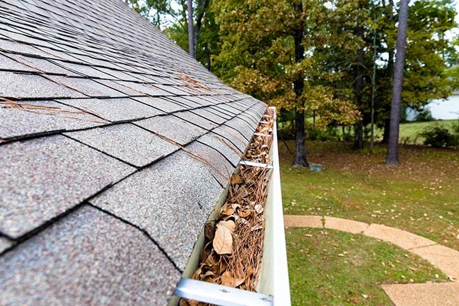 worker cleaning leaves and debris from gutters